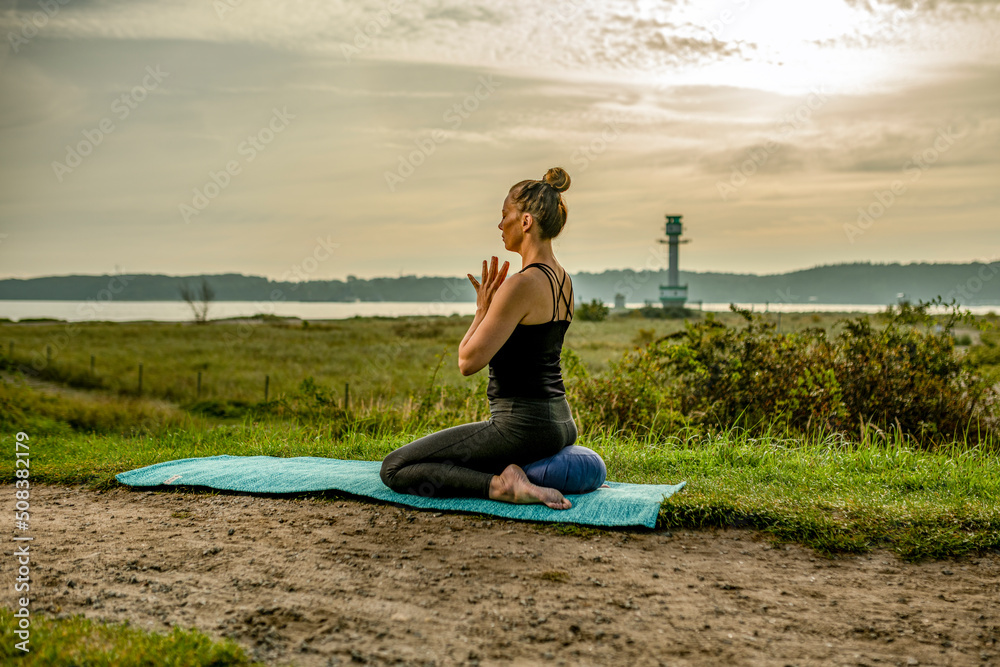 Fototapeta premium a woman is exercising Yoga at the beach