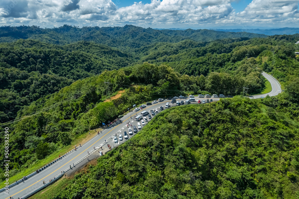 Many cars have parked in the parking area at the zigzag road is similar to the number 3. This road is built on a mountain, past the forest in Nan, Thailand.