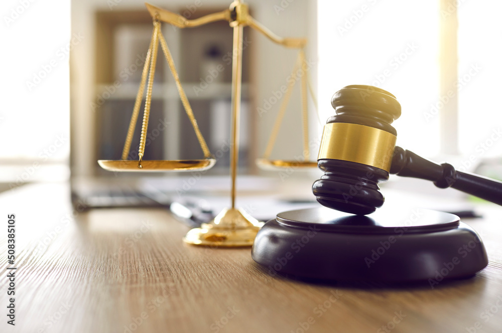 Brown judge's gavel on sound block and scales of justice on table in judge's office. Close up of wooden judge's gavel for making final decision. Law and justice concept. Soft focus. Brown judge's gavel on sound block and scales of justice on table in judge's office. Close up of wooden judge's gavel for making final decision. Law and justice concept. Soft focus.
