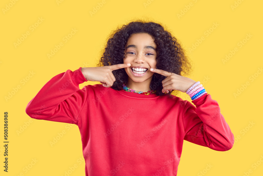 Portrait of excited funny African American teen girl in casual wear isolated on yellow studio background show smile. Overjoyed biracial kid feel joyful and optimistic share positivity and happiness. Portrait of excited funny African American teen girl in casual wear isolated on yellow studio background show smile. Overjoyed biracial kid feel joyful and optimistic share positivity and happiness.