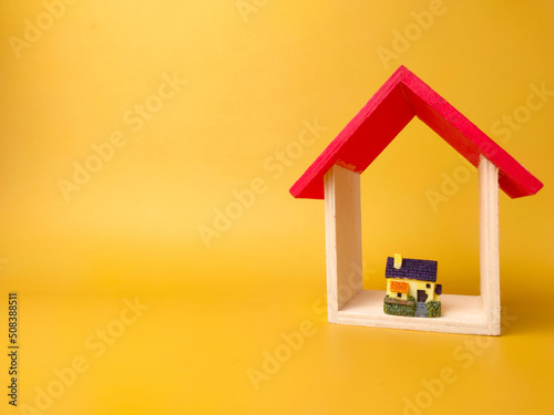 Toy house and miniature house isolated on yellow background with copy space