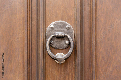Vintage forged door knocker in the wooden door
