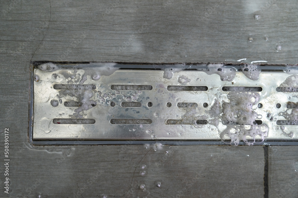 Drain hole with pipe cleaner in metal sink. Foam with bubbles of