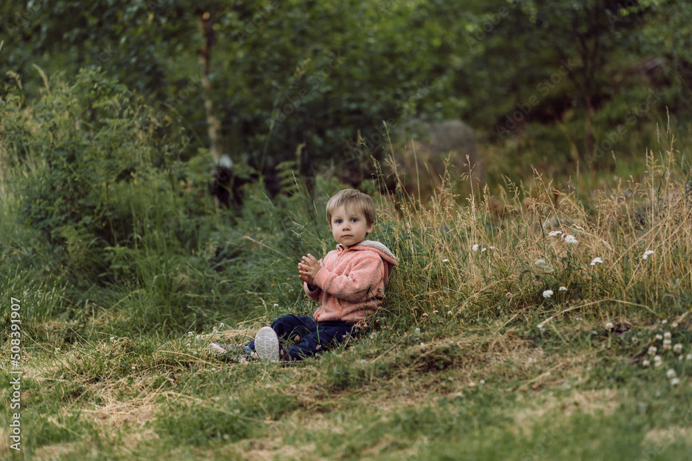 cute little caucasian boy sitting alone on grass cute little caucasian boy sitting alone on grass