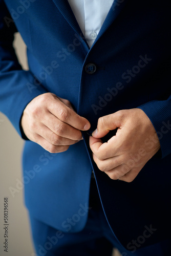 the groom's hands fasten the suit in the morning before the wedding. close-up of a man
