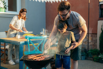 father and son grilling barbecue in backyard
