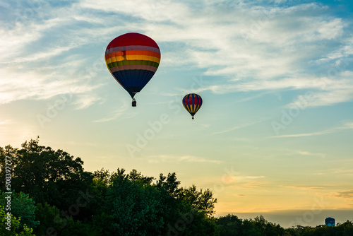 Hot Air Balloon over the trees with white clouds and golden sunset © John G Rusfeldt