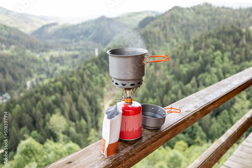 Photography Preparing food for hiking with special dishware and portable gas burner on mountains background