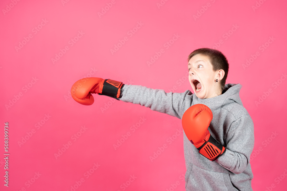 Angry aggressive boy punching copy space isolated on pink background. Violence on childhood concept. Angry aggressive boy punching copy space isolated on pink background. Violence on childhood concept.
