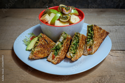 Pesto Chicken Sandwich mit Tomaten, Mozarella und Obstsalat photo