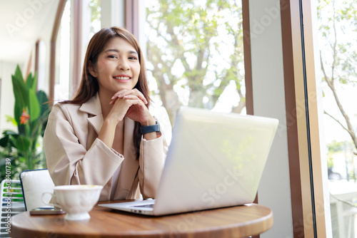 Asian woman smiling and working by laptop in the coffee shop. Business concept.