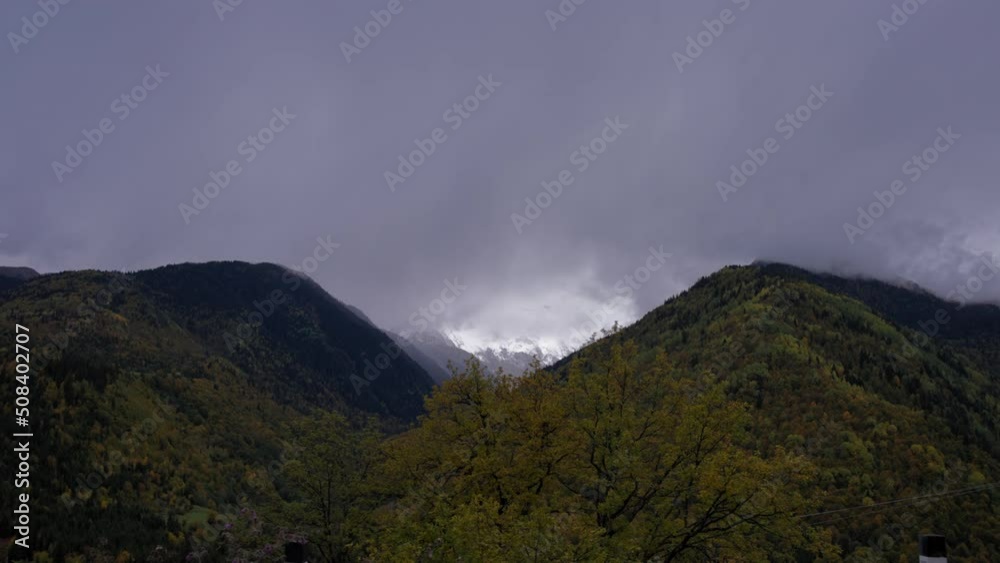 Driving by mountain hills covered in colorful trees during autumn season and high snowy peaks. Driving by mountain hills covered in colorful trees during autumn season and high snowy peaks.