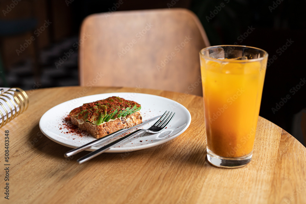Avocado toast on the whole wheat bread with glass of fresh orange and sea buckthorn sugar free lemonade for the breakfast Avocado toast on the whole wheat bread with glass of fresh orange and sea buckthorn sugar free lemonade for the breakfast