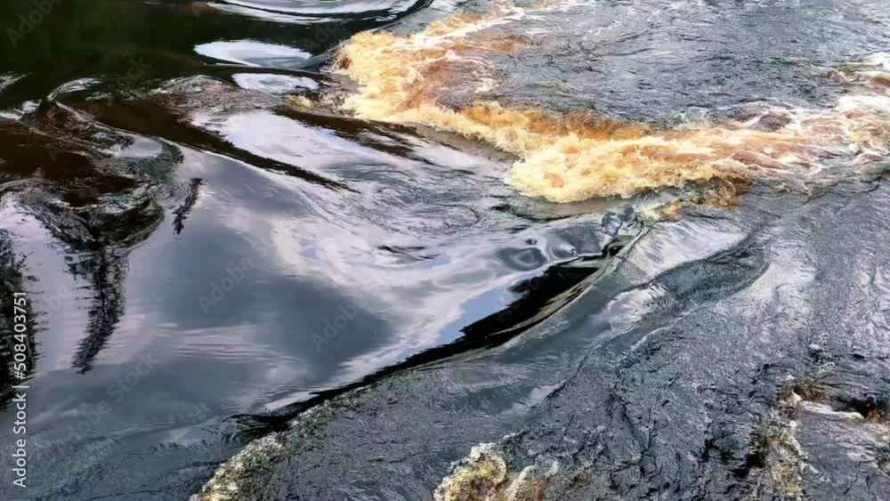The river is dark brown in color flowing with the flow, the irregularities of the water are visible due to the stones. High quality 4k footage The river is dark brown in color flowing with the flow, the irregularities of the water are visible due to the stones. High quality 4k footage
