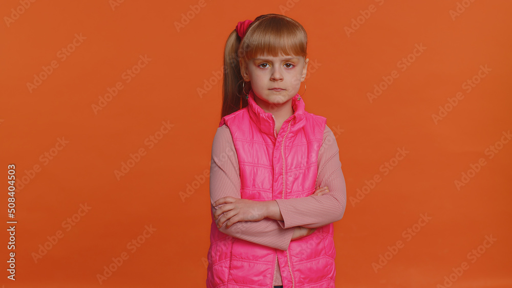 Dissatisfied girl shaking head No, asking reason of failure, expressing disbelief irritation, feeling bored, disappointed in result, bad news. Little child isolated on orange studio wall background Dissatisfied girl shaking head No, asking reason of failure, expressing disbelief irritation, feeling bored, disappointed in result, bad news. Little child isolated on orange studio wall background