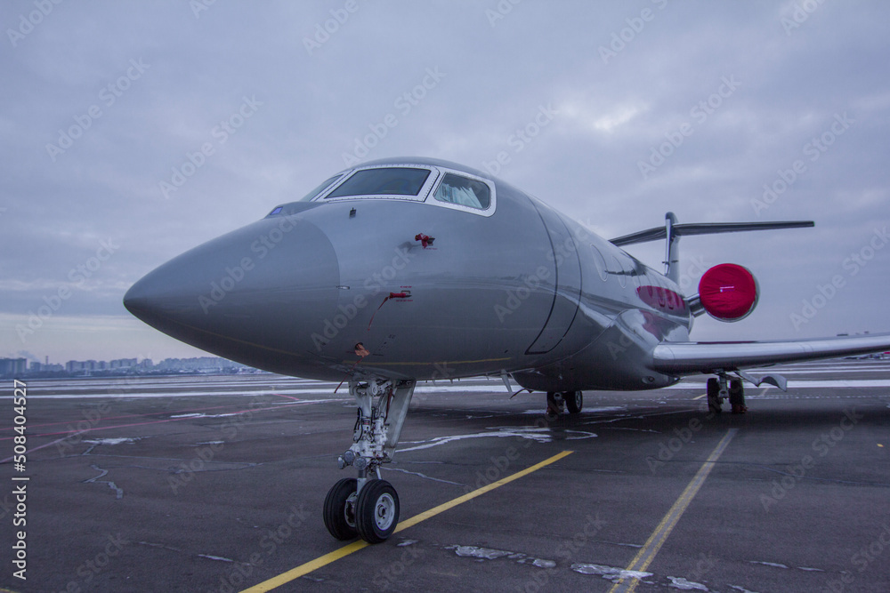 Private jet parked at the airport with engine plugs on against a cloudy sky Private jet parked at the airport with engine plugs on against a cloudy sky