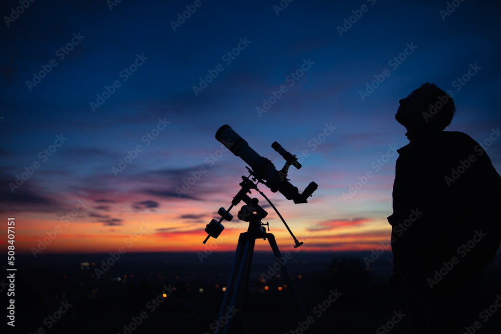 Silhouette of a man, telescope and countryside under the starry