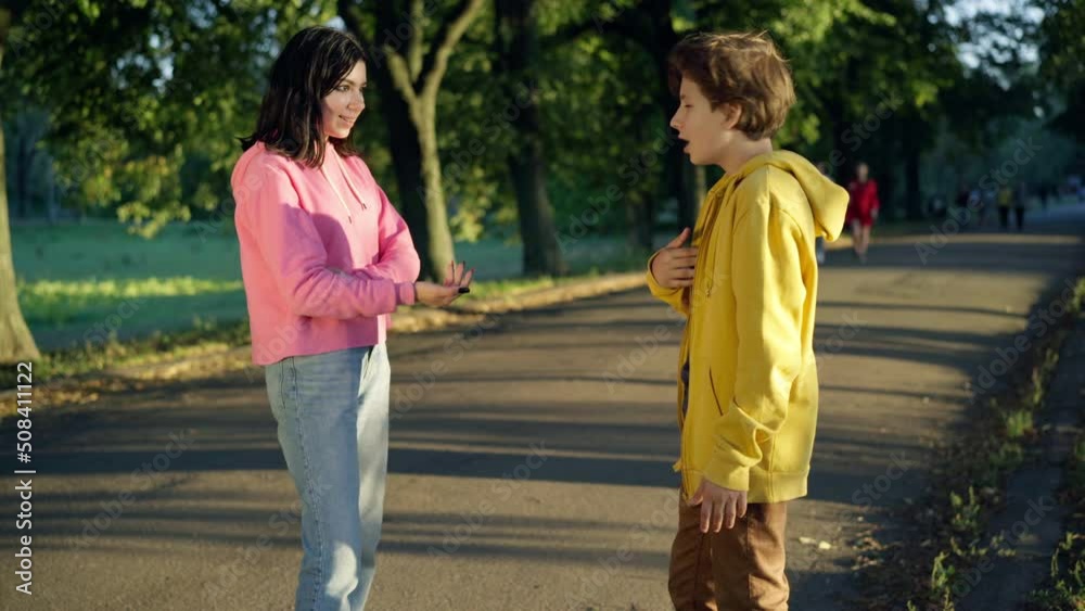Angry teenage boy arguing with girl standing on park alley outdoors. Side view portrait of unsatisfied Caucasian teen boyfriend quarreling with girlfriend talking gesturing. Relationship problems Angry teenage boy arguing with girl standing on park alley outdoors. Side view portrait of unsatisfied Caucasian teen boyfriend quarreling with girlfriend talking gesturing. Relationship problems