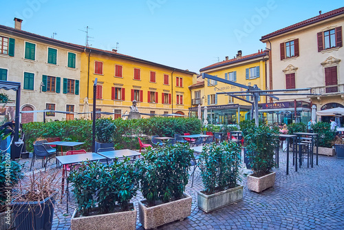 Green plants around cozy outdoor restaurants, Giuseppe Mazzini Square, Como, Italy photo