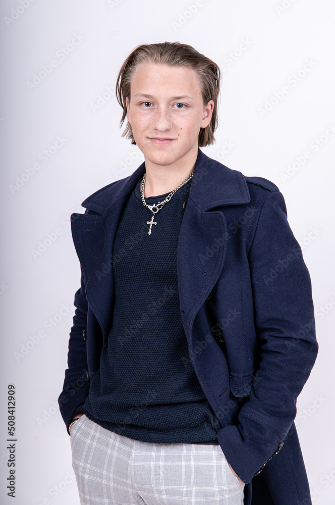 Porträt junger lächelnder Mann mit langen Haaren mit blauem Pullover und Mantel