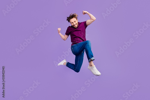 Full length photo of young excited man jumper fists hands awesome isolated over violet color background