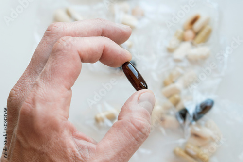 Male hand holding gelatin  bioactive dietary supplement pill. photo