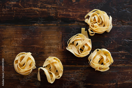 Raw fettuccine noodles are on the wooden kitchen table. View from the top point. Copy space.