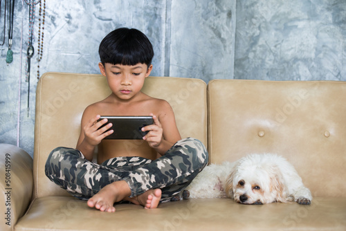 Boy using mobile phone relaxing at home. Puddle dog is a friend to stay beside. 