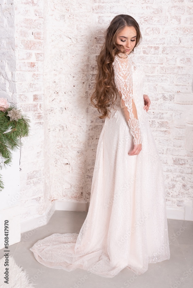 Fototapeta premium The bride in full growth, against the backdrop of a white brick wall.