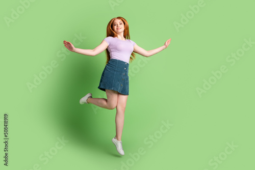 Full length photo of young lovely girl jumper energetic good mood isolated over green color background