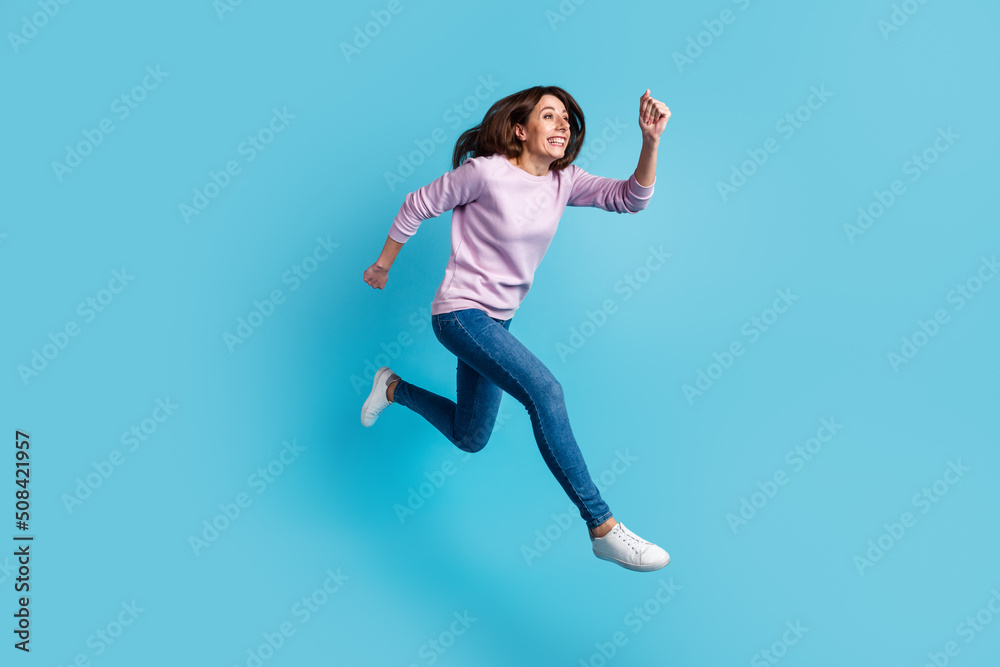 Fototapeta premium Full size profile side photo of young cheerful woman have fun rush speed jump isolated over blue color background