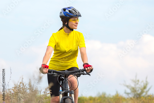 Beautiful woman in yellow riding a bike in nature. Sports and recreation. Hobbies and health.