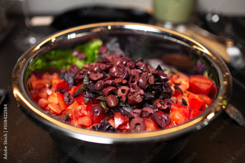 Close-up of steel bowl with prepared ingredients for salad.