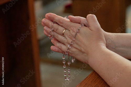 Christian religion background with light bokeh christian woman hand on holy bible praying to god holding cross rosary selective focus at cross. concept of christian religious people faith and practise