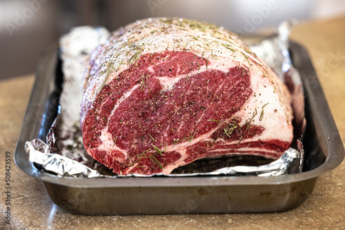 Φωτογραφία Raw prime rib roast seasoned and sitting on an aluminum foil lined pan ready for
