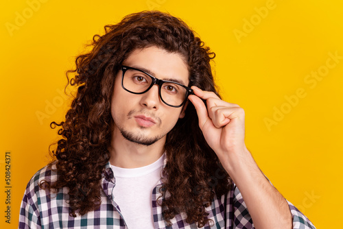 Photo of young serius guy hand touch eyeglasses confident clever isolated over yellow color background photo