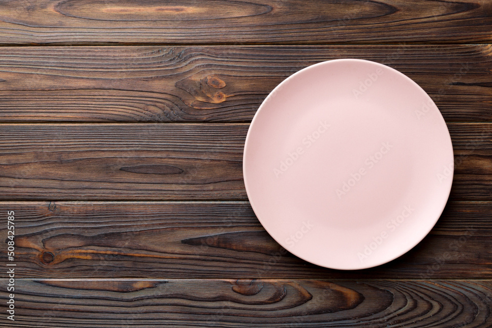 Top view of empty pink plate on wooden background. Empty space for your design Top view of empty pink plate on wooden background. Empty space for your design