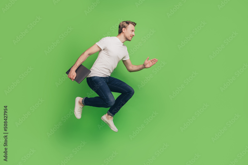 Profile photo of sporty businessman hold laptop jump hurry run wear white t-shirt on green color background Profile photo of sporty businessman hold laptop jump hurry run wear white t-shirt on green color background
