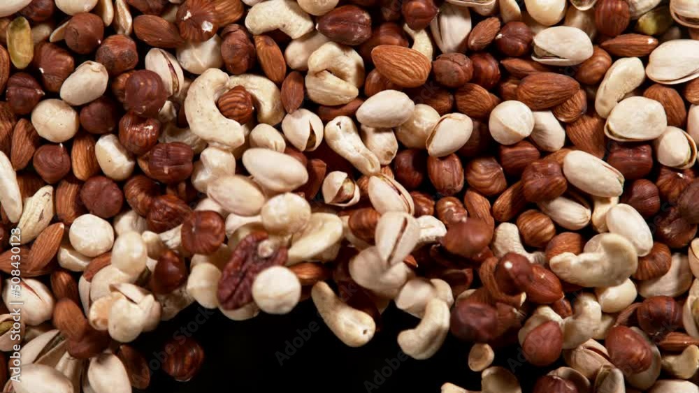 Super slow motion of blowing mix nuts on black background. Filmed on high speed cinema camera, 1000 fps.