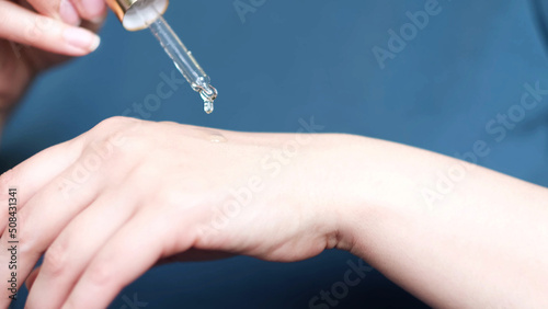unrecognizable woman dropping collagen moisturizer into her hand at home