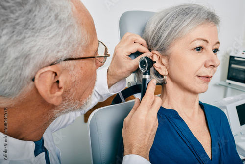 Otolaryngologist doctor checking senior woman's ear using otoscope or auriscope at medical center. Hearing test for older people, otoscopy