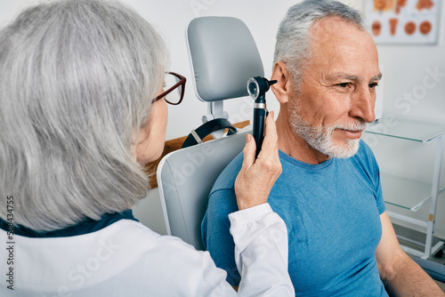 Senior man during ear test with audiologist at audiology. Diagnosis of impairment and hearing testing to senior people, otoscopy