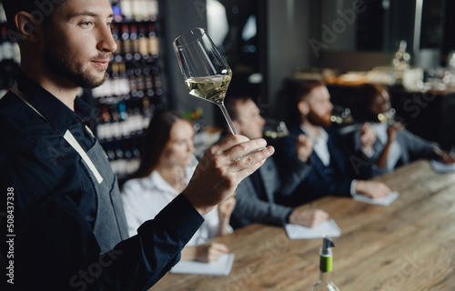 Professional sommelier conducts white wine tasting for business company in restaurant