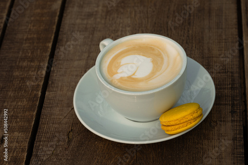 Cup of cappuccino with yellow macaron