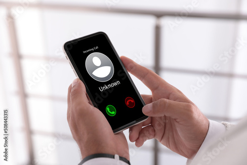 Fotótapéta Man deciding answer incoming call from unknown caller or not indoors, closeup