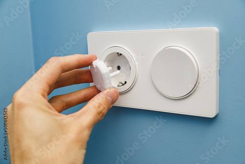 Safety plug for an electrical outlet, protecting a child from electric shock on a blue background