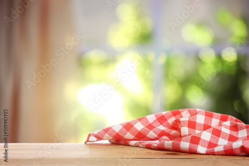 Red and white checkered tablecloth on wooden table indoors, space for design. Bokeh effect