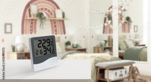 Digital hygrometer with thermometer on white table in children's room. Low humidity level for kids