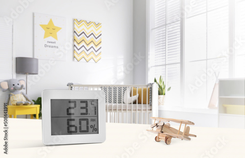 Digital hygrometer with thermometer on white table in children's room. Optimal humidity level for kids photo