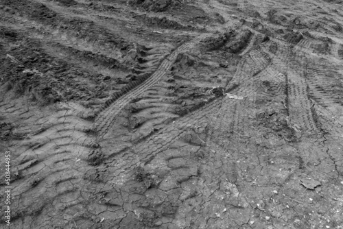 Different tire tracks on dry clay soil in black and white